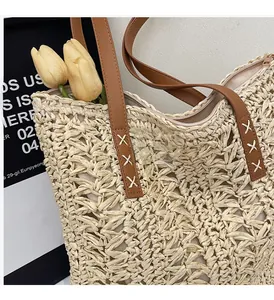 Detail of straw tote bag showing hollow weave texture and brown faux leather handles