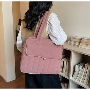Detail der rosa gesteppten Einkaufstasche aus weichem Nylon in Bibliothekskulisse