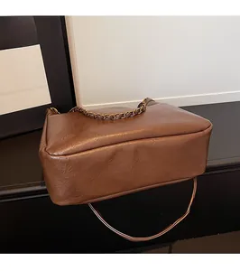 Detailed side view of dark brown tote bag showing textured leather and round metal handle