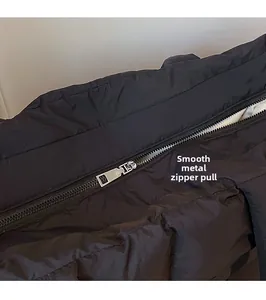Macro detail of high-quality smooth metal zipper pull on black quilted puffer tote bag