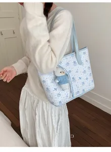 Detalle del bolso tote azul claro con estampados de dibujos y colgante de oso