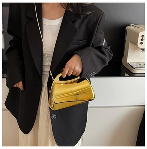 Detail of glossy gold acrylic evening bag featuring a unique geometric shape and chain strap
