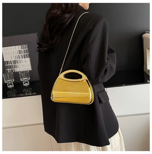 Back view of a model wearing a shiny gold acrylic evening bag with a metal chain strap