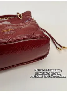 Detail showing the reinforced thick base and wine red quilted leather of the bucket bag