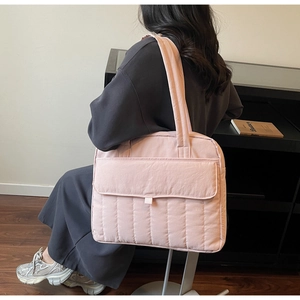 Detail einer großen rosa gesteppten Tragetasche mit vertikalen Nähten und breitem Gurt
