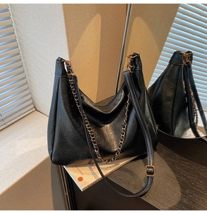 Detailed view of the black tote bag showing vintage pleated texture and gold chain strap