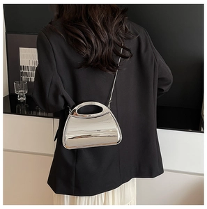 Silver mirror acrylic clutch with metal chain strap shown on a black suit jacket