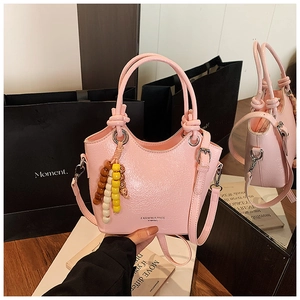 Détail d'un sac seau rose brillant avec texture grainée et charm en perles colorées