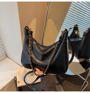Detail of black leather crescent tote bag with gold chain and mirror reflection view