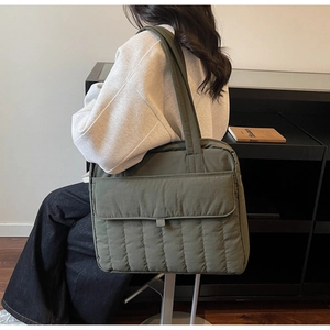 Detail einer olivgrünen gesteppten Tragetasche mit großer Vordertasche und Nylonmaterial