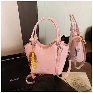 Sac seau rose en cuir verni avec poignée, breloque perlée et reflet miroir détaillé