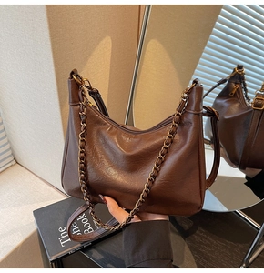 Detail of vintage dark brown tote bag showing glossy leather texture and chain strap
