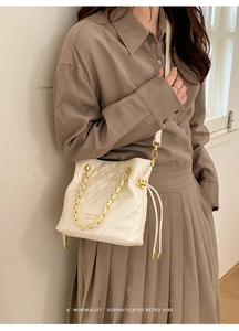 Sac seau matelassé blanc avec chaîne dorée dans un cliché de mode minimaliste et élégant