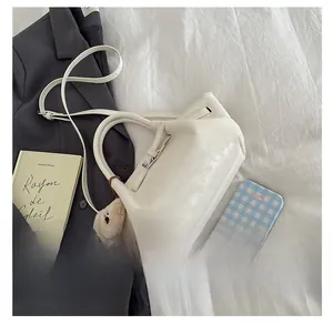 Detail view of white bucket bag with cute bear charm and adjustable shoulder strap