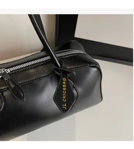 Detail of black leather Boston bag featuring silver zipper and golden logo leather tag