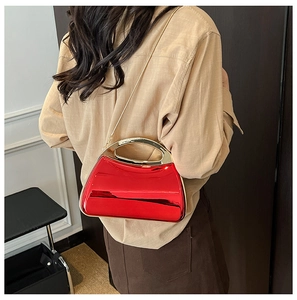 Detail view of glossy red acrylic evening bag with chunky gold handle and chain strap