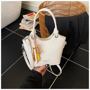 Détail du sac seau blanc en similicuir avec logo et breloques en perles de bois colorées