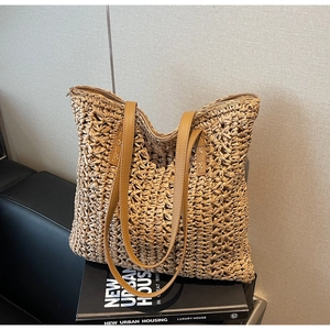 Detail of hand-woven straw tote bag showing brown leather handles and zipper closure