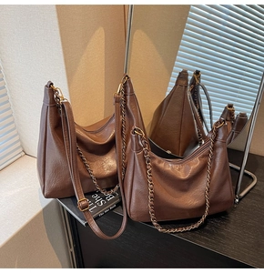 Detail view of deep brown vintage tote bag with gold chain and litchi grain texture