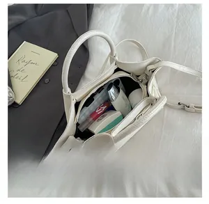 Top view of open white leather bucket bag interior with compartments and personal items