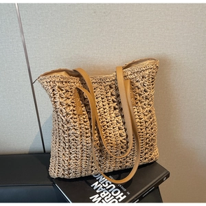 Close-up of minimalist straw tote bag with brown leather handles and woven texture details