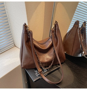 Close-up of vintage brown leather tote bag with metallic chain and adjustable strap
