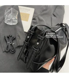 Detailed close-up showing the adjustable buckle on a black glossy leather shoulder bag