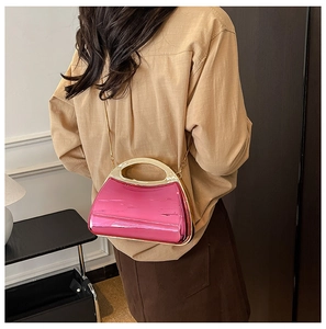 Model wearing a glossy fuchsia acrylic clutch with a gold chain and metallic handle