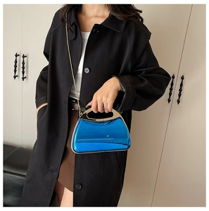 Blue acrylic mirror晚宴包 bag with gold metal handle and chain strap on black outfit