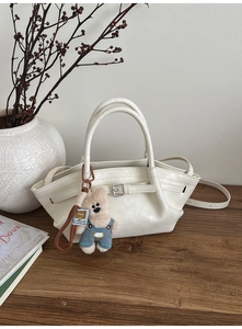 Chic beige leather bucket bag with a cute bear charm in a minimalist lifestyle setting