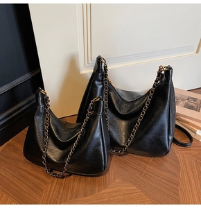 Macro detail showing two sizes of black vintage leather tote bags with gold chain straps