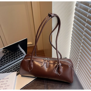 Detailed close-up of dark brown baguette shoulder bag with metal zipper and fine texture