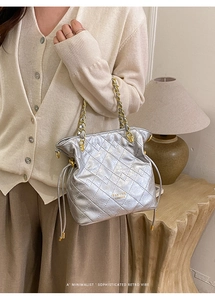 Détail du sac seau matelassé argenté avec bandoulière chaîne et logo de marque