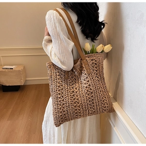 Detailed close-up of a woven straw tote bag with brown straps and tulip flowers