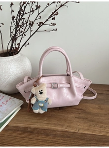 Pink bucket bag with leather texture, decorative buckle, and cute bear plush charm detail