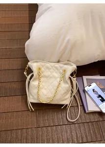 Détail d'un sac seau en cuir matelassé avec bandoulière en chaîne dorée et cordon de serrage