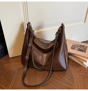 Detailed macro view of dark brown faux leather hobo tote with metallic chain