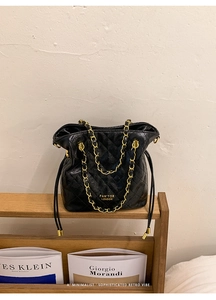 Détail du sac seau en cuir matelassé noir avec bandoulière chaîne dorée exposée