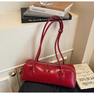 Detail of red leather baguette bag with dual shoulder straps and gold logo lettering