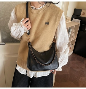 Detail of vintage black tote bag with gold chain strap on model in home setting