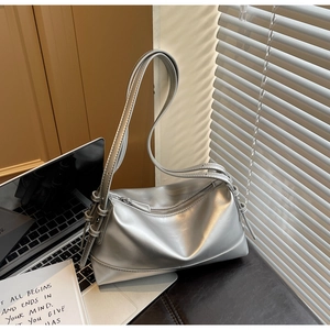 Minimalist silver shoulder bag with knotted strap detail shown in a lifestyle setting