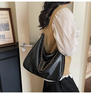Detailed side view of black vintage tote bag with gold chain strap and large capacity