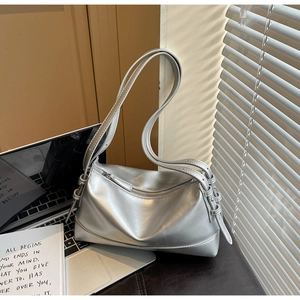 Detail of silver metallic shoulder bag showing shiny texture and adjustable strap buckle