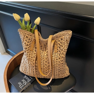 Close-up of woven straw tote bag with brown PU leather handles and durable zipper closure