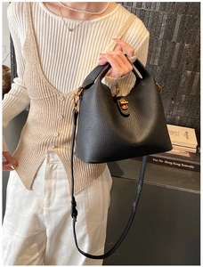Détail du sac seau noir en cuir avec fermoir doré porté par un mannequin