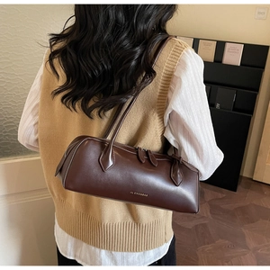 Close-up of a vintage dark brown baguette shoulder bag worn over the shoulder in a cozy setting
