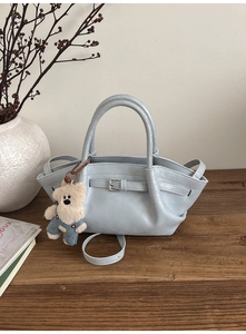 Detail of light blue leather bucket bag with silver buckle and plush bear charm
