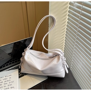 Detail view of a lavender glossy leather underarm bag with zipper on a minimalist desk