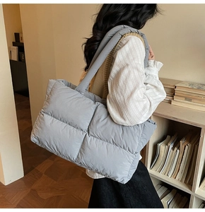 Macro view of light grey quilted puffer tote bag showing spacious interior for laptops