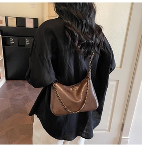 Detail of vintage brown leather tote bag featuring a retro chain and matte texture on model